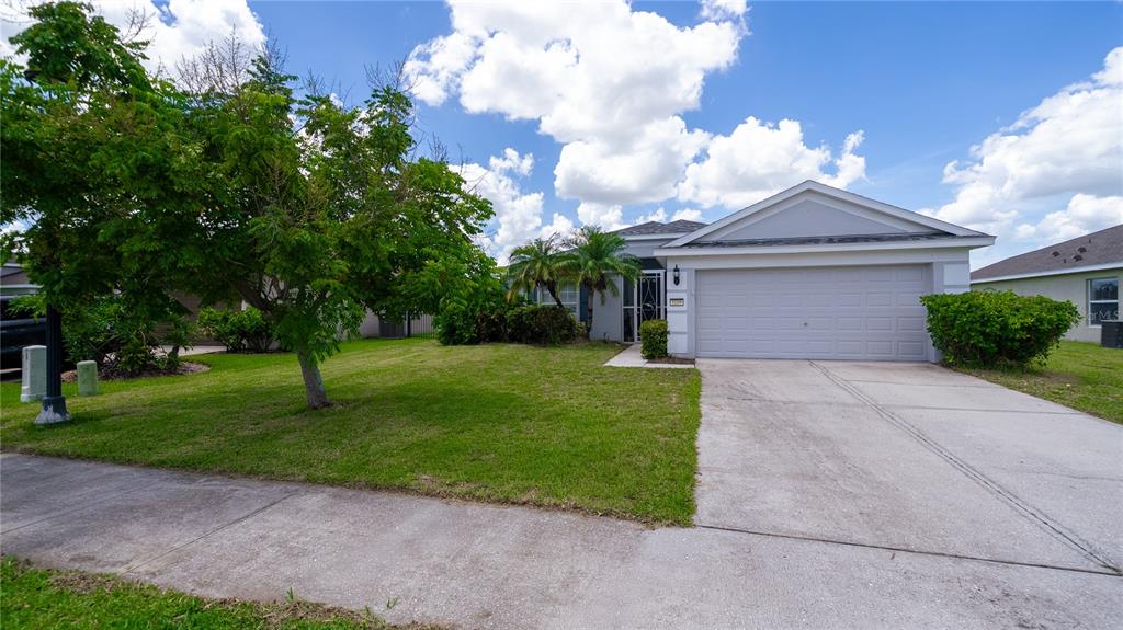 A single-story house with a two-car garage, a concrete driveway, and a green front lawn — 5109 99TH AVENUE E, PARRISH, FL