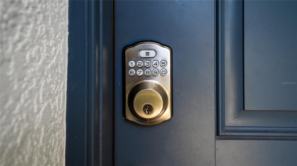 A close-up view of a brushed metal electronic keypad deadbolt on a blue door — 5109 99TH AVENUE E, PARRISH, FL