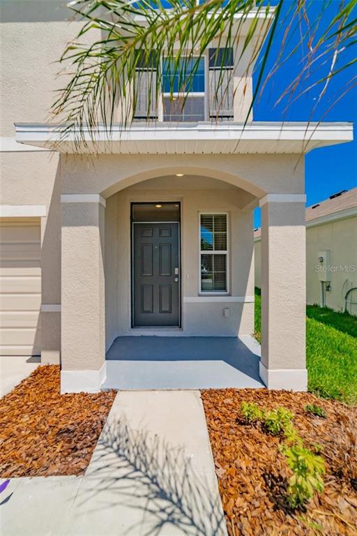 The exterior view shows a covered front porch with a dark door and a walkway — 9138 FORGE BREEZE LOOP, WESLEY CHAPEL, FL