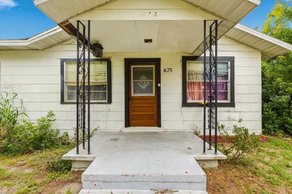 The exterior of a single-story house features a concrete porch with two decorative metal columns — 675 E BAY AVENUE, EAGLE LAKE, FL