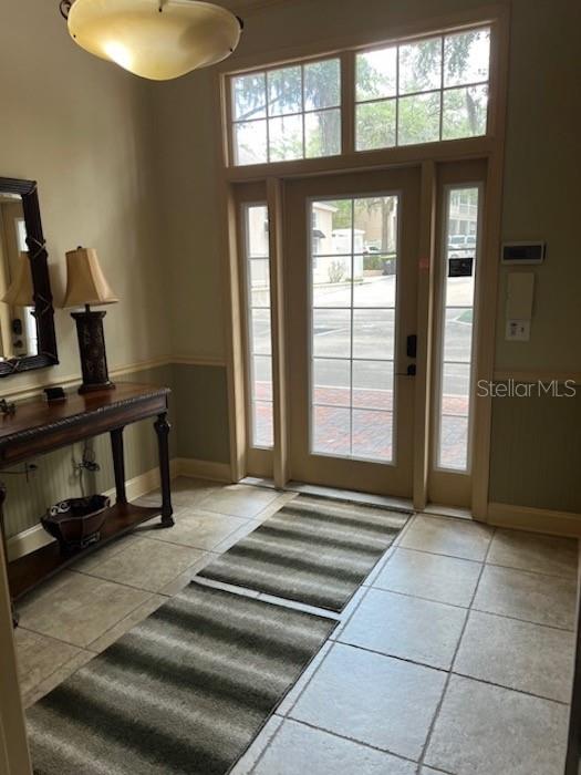 A tiled entryway features a wooden console table, a lamp, and a glass-paneled front door — 5216 SW 91ST TERRACE, GAINESVILLE, FL