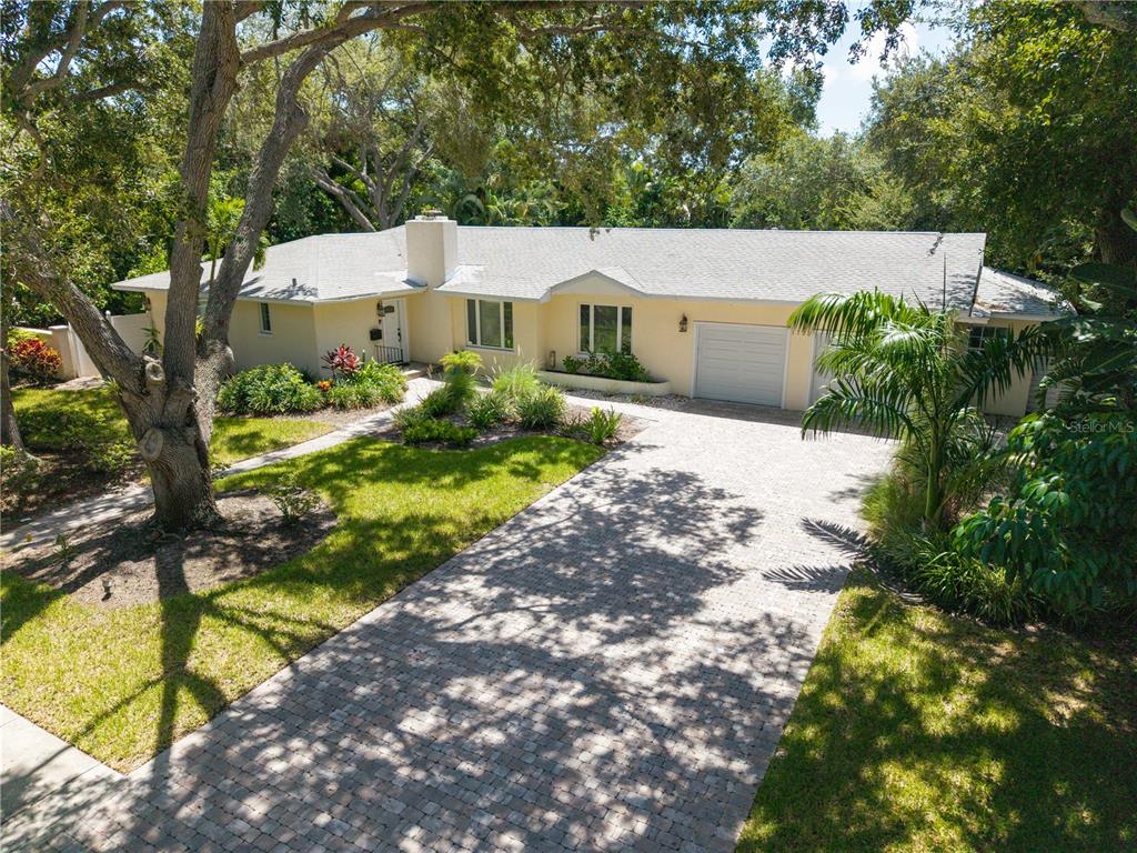 A single-story house with a light yellow exterior, a paved driveway, and mature trees — 1722 NORTH DRIVE, SARASOTA, FL