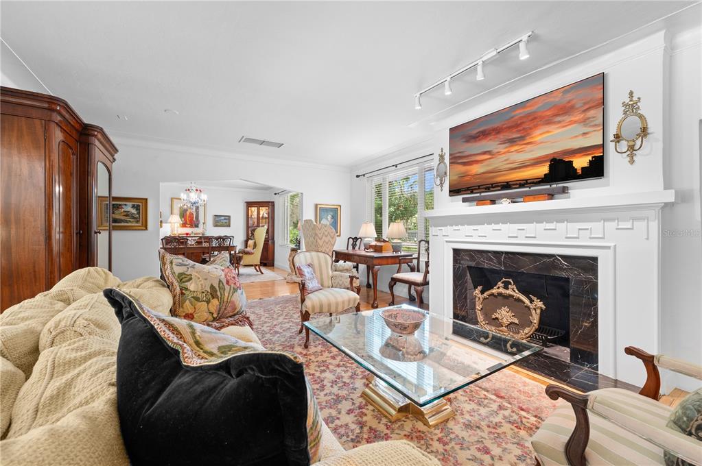 A living room features a fireplace with a mounted television, a glass coffee table, and furniture — 1722 NORTH DRIVE, SARASOTA, FL