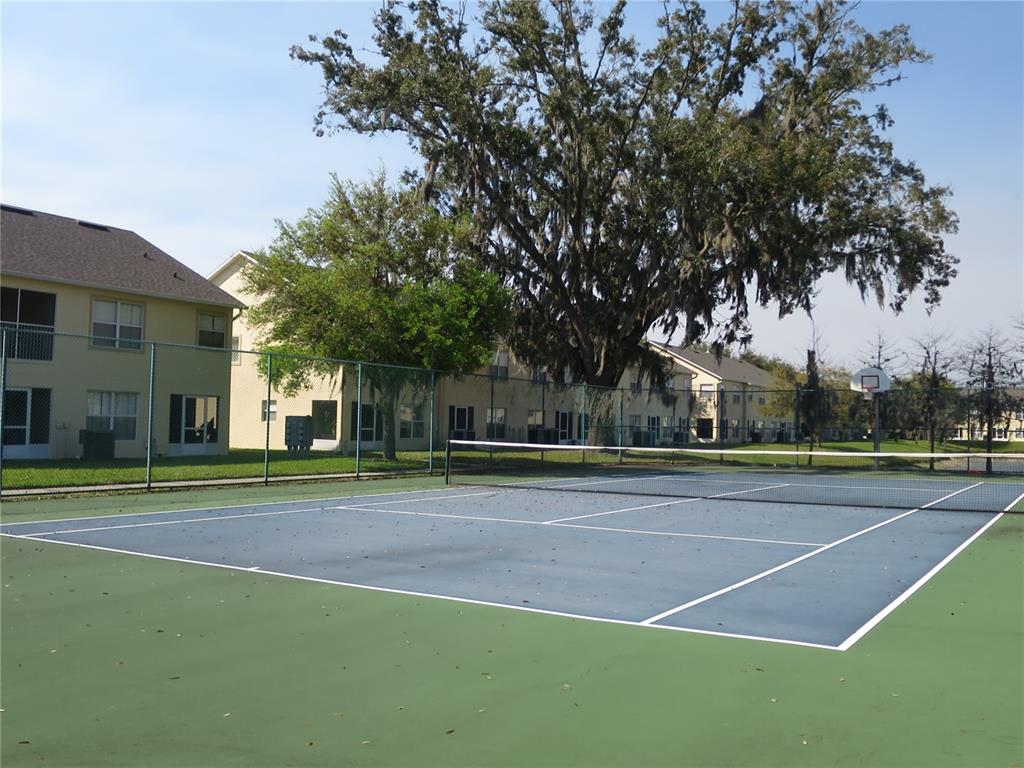 A tennis court with a basketball hoop sits in front of multi-story apartment buildings — 2806 CLUB CORTILE CIRCLE UNIT B, KISSIMMEE, FL