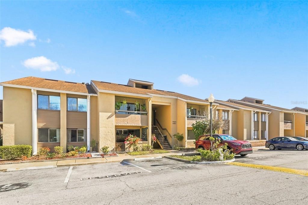 A multi-story apartment building with tan stucco siding and a parking lot in front — 5195 VINELAND ROAD UNIT B102, ORLANDO, FL