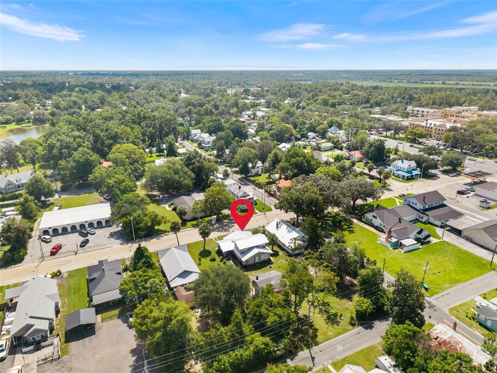 An aerial view shows a residential property marked with a red pin among trees — 398 S MARION AVENUE, LAKE CITY, FL
