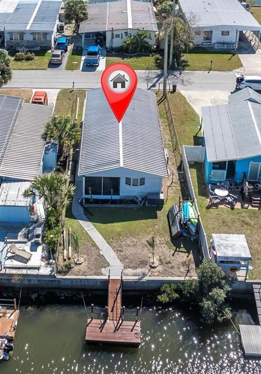 An aerial view shows a waterfront house with a private dock and a metal roof — 6627 TOWER DRIVE, HUDSON, FL