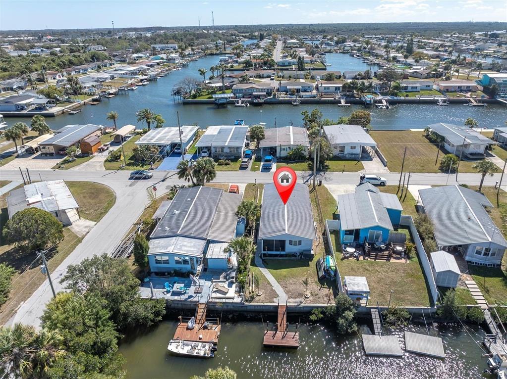 An aerial view shows a waterfront mobile home with a private dock and canal access — 6627 TOWER DRIVE, HUDSON, FL