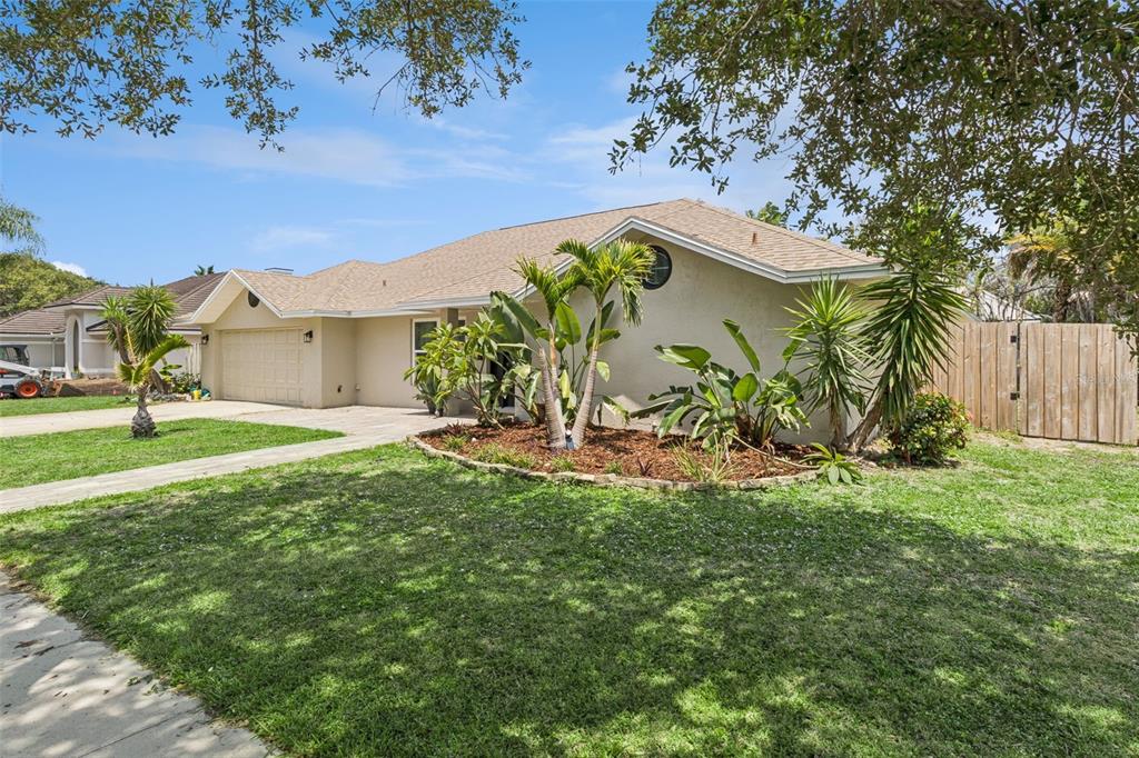A single-story house with a beige stucco exterior, a two-car garage, and a landscaped yard — 105 TRADEWINDS TER, INDIALANTIC, FL