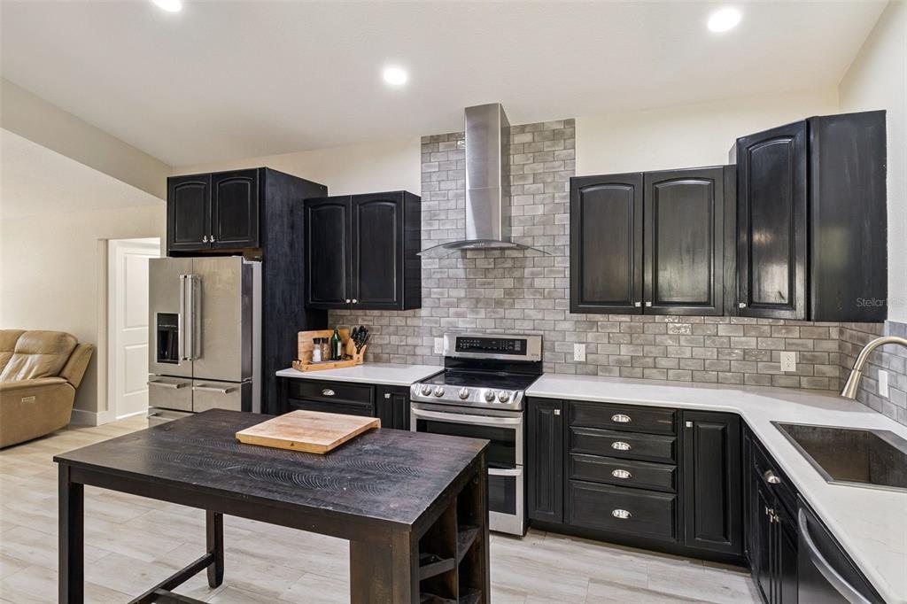 A kitchen features black cabinets, a stainless steel range, and a gray subway tile backsplash — 105 TRADEWINDS TER, INDIALANTIC, FL