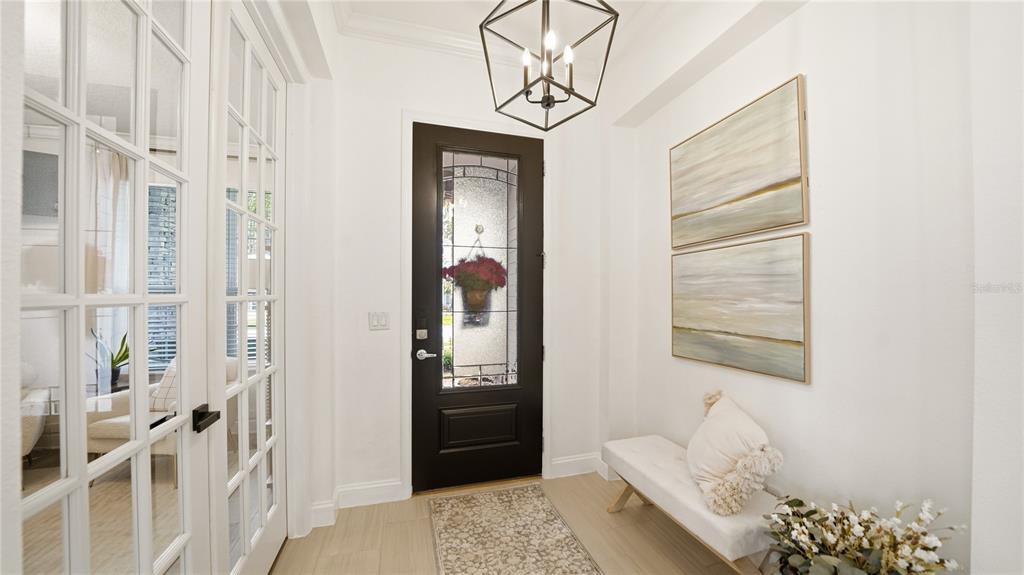 A bright entryway features a dark front door, a white bench, and a geometric chandelier — 2931 LAS CALINAS BOULEVARD, ST AUGUSTINE, FL