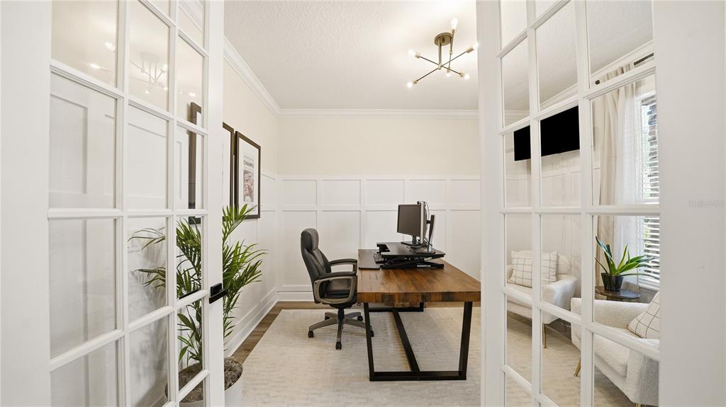 A home office features a wooden desk, white wainscoting, and glass-paned double doors — 2931 LAS CALINAS BOULEVARD, ST AUGUSTINE, FL