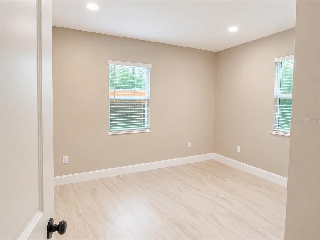 An empty bedroom with light-colored wood-look flooring, beige walls, and two windows with blinds — 2103 45TH STREET COURT E, BRADENTON, FL