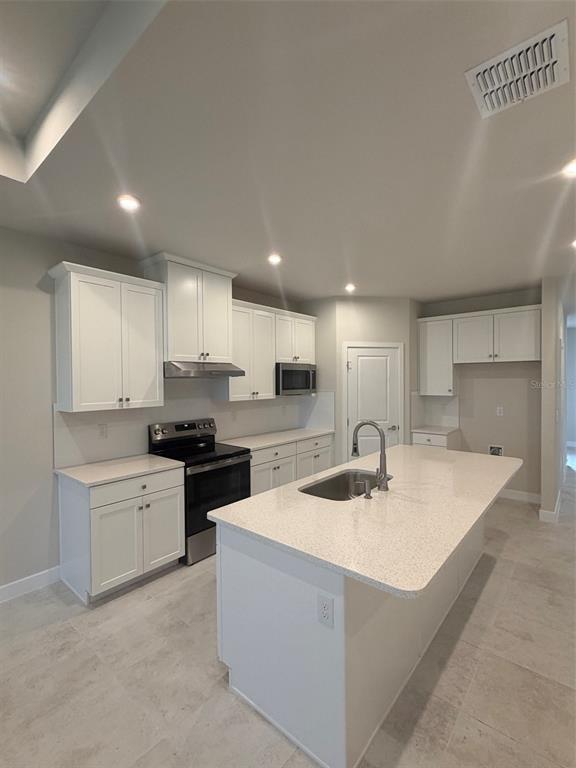 An open-concept living and dining area features light wood furniture, neutral decor, and tile flooring — 18740 HIGHLAND DEW STREET, SPRING HILL, FL