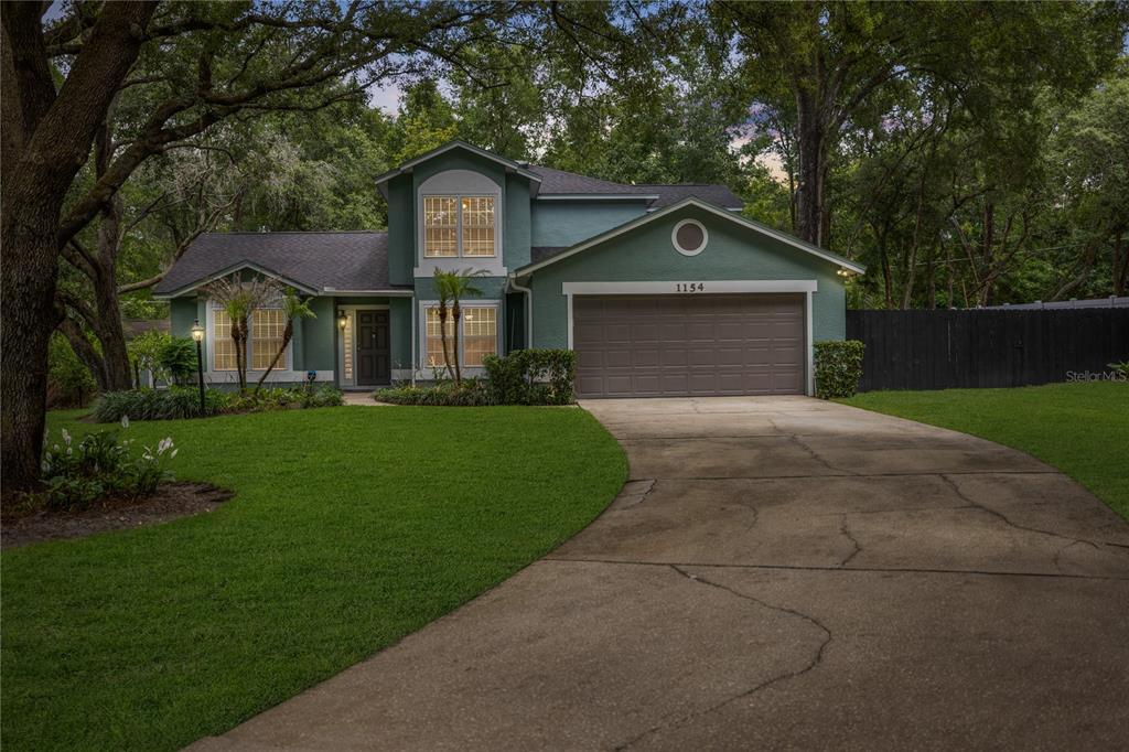 A two-story green house with a concrete driveway and a two-car garage — 1154 DEER LAKE CIRCLE, APOPKA, FL