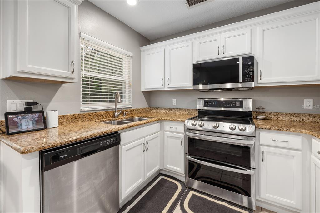 A kitchen with white cabinets, stainless steel appliances, and speckled granite countertops — 1154 DEER LAKE CIRCLE, APOPKA, FL
