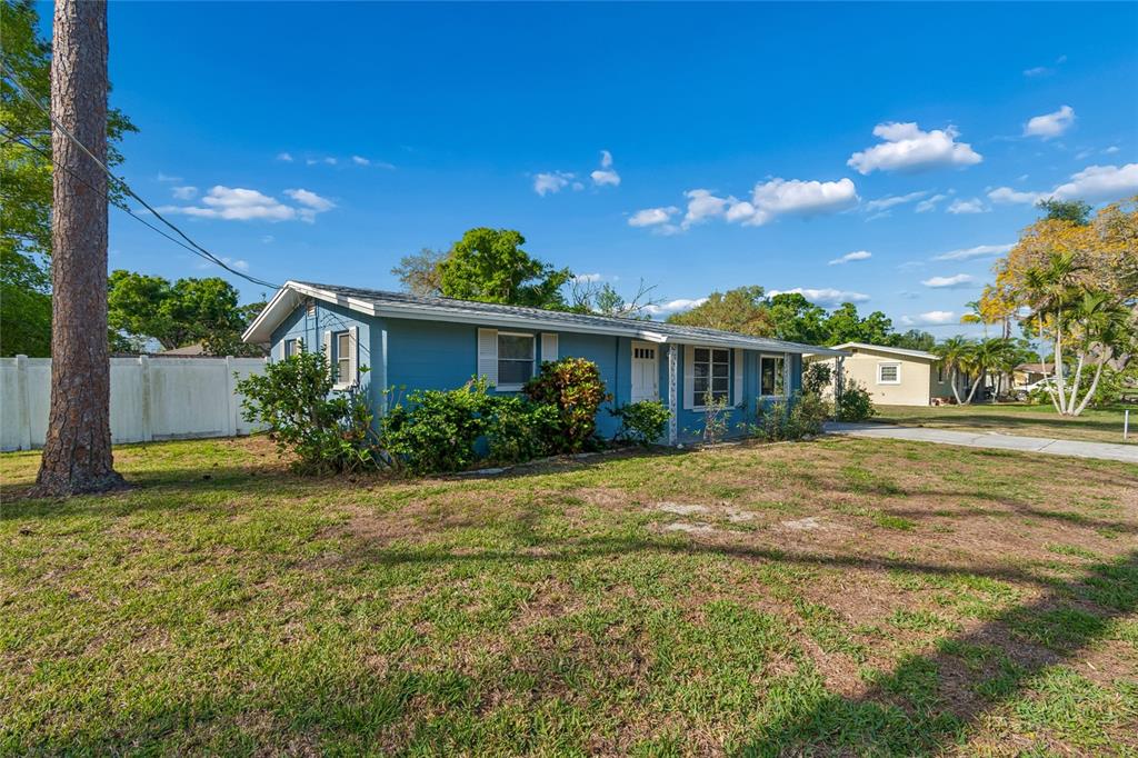 A blue single-story house with a white door and shutters sits on a grassy lot — 2348 DOUD STREET, SARASOTA, FL