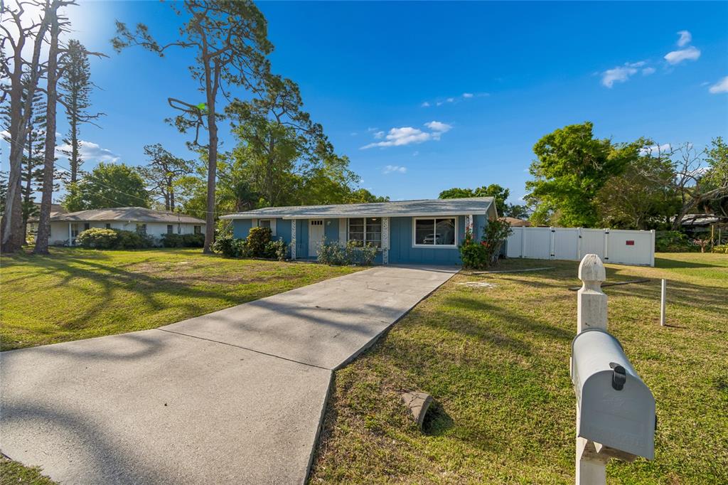 A blue single-story house with a concrete driveway and a white fence — 2348 DOUD STREET, SARASOTA, FL