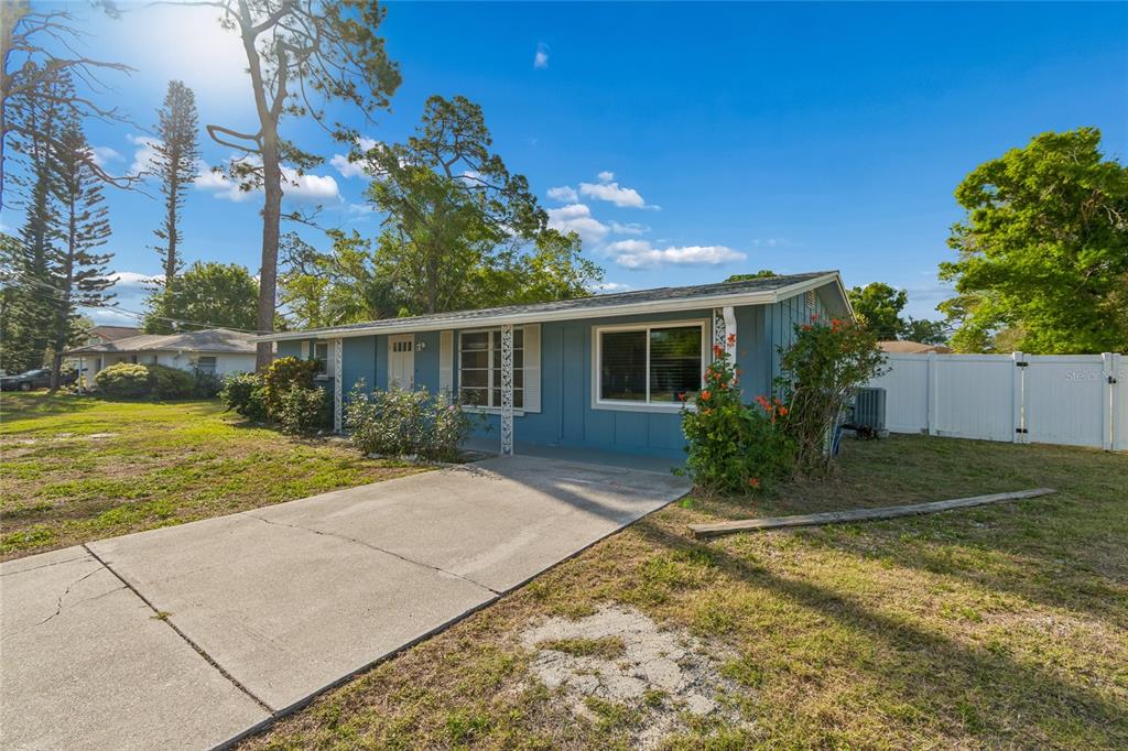 A blue single-story house with a concrete driveway and a white fence in the yard — 2348 DOUD STREET, SARASOTA, FL