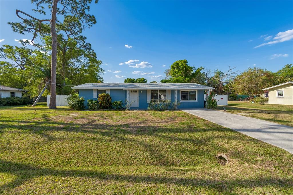 A single-story blue house with a white front door and a concrete driveway — 2348 DOUD STREET, SARASOTA, FL