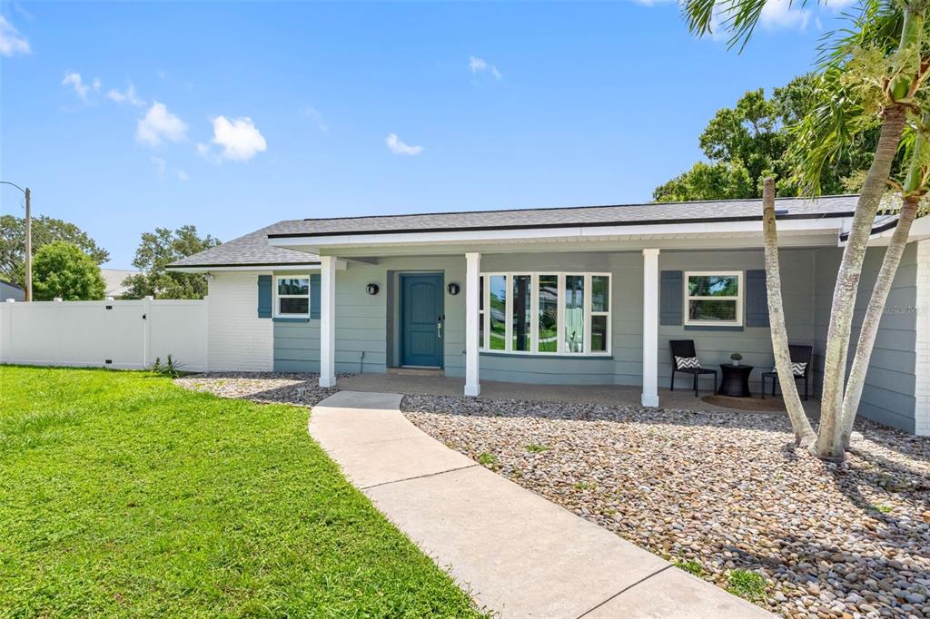A single-story house with light blue siding, a covered porch, and a concrete walkway — 1950 ARVIS CIRCLE W, CLEARWATER, FL