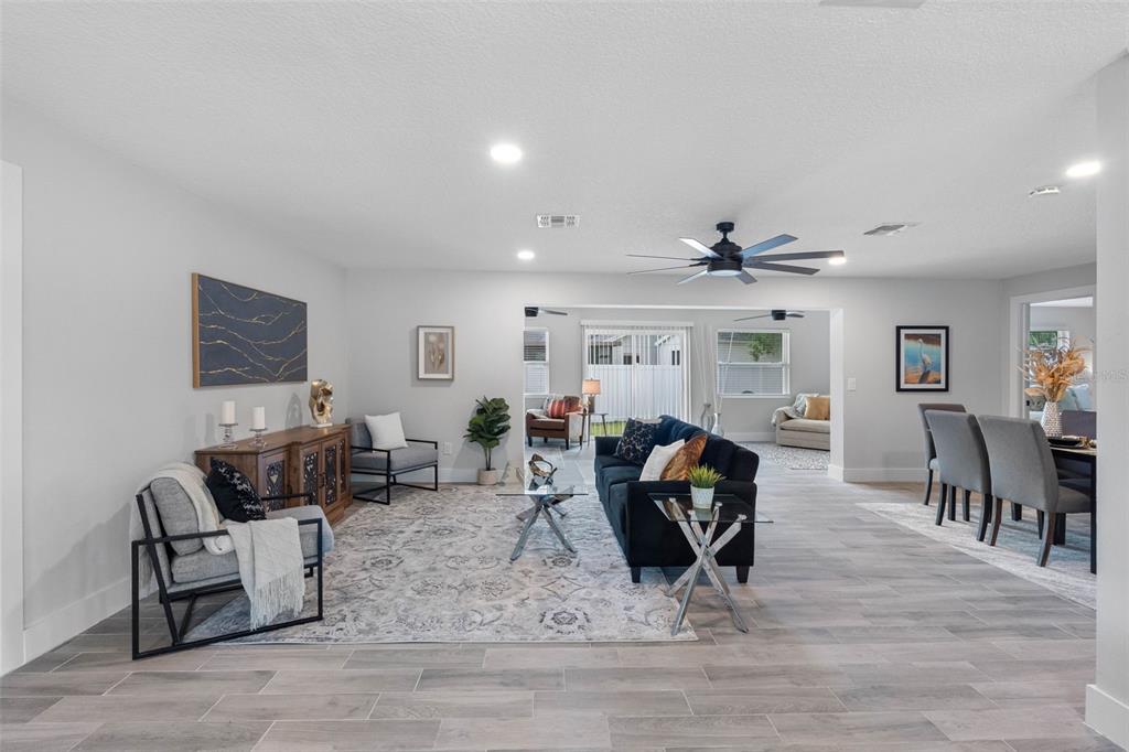 A living room with gray tile floors, a black sofa, and an open floor plan — 1950 ARVIS CIRCLE W, CLEARWATER, FL