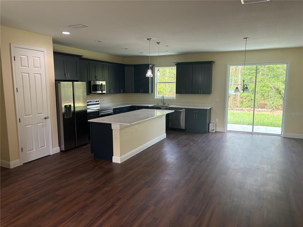 A single-story house with a green garage door and a concrete driveway sits among trees — 6860 SW 135TH TERRACE ROAD, OCALA, FL