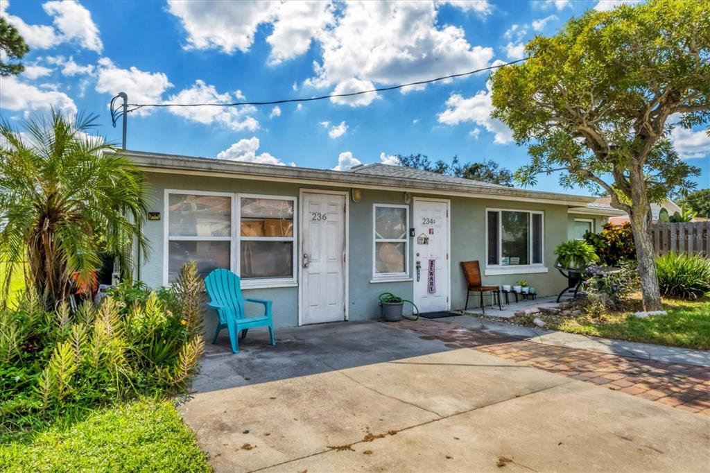 A single-story duplex with two white doors, a concrete driveway, and a blue chair — 234/236 COLONIA LANE E, NOKOMIS, FL