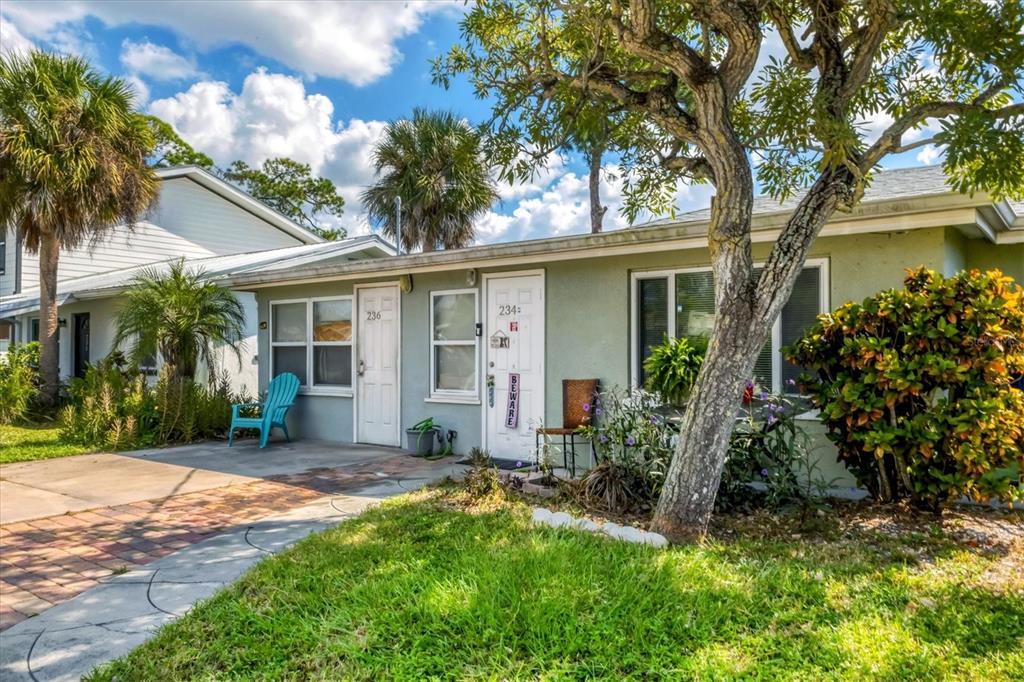 A single-story duplex with light green siding, two white doors, and a paved walkway — 234/236 COLONIA LANE E, NOKOMIS, FL