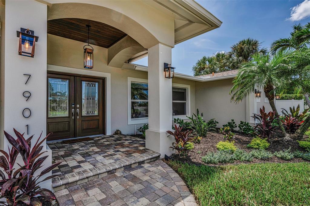 The exterior entrance features a paved walkway, double wooden doors, and a covered porch area — 7901 10TH AVENUE S, ST PETERSBURG, FL