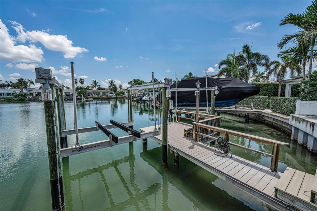 A boat lift and wooden dock extend into a canal with a covered boat nearby — 7901 10TH AVENUE S, ST PETERSBURG, FL
