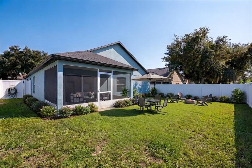A backyard features a screened-in patio, a dining set under an umbrella, and a fire pit — 127 ABERDEEN STREET, DAVENPORT, FL