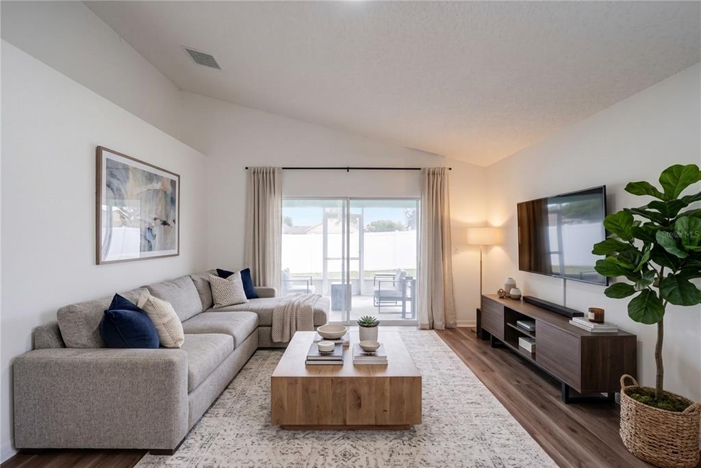 A living room features a grey sectional sofa, wooden coffee table, media console, and large plant — 127 ABERDEEN STREET, DAVENPORT, FL