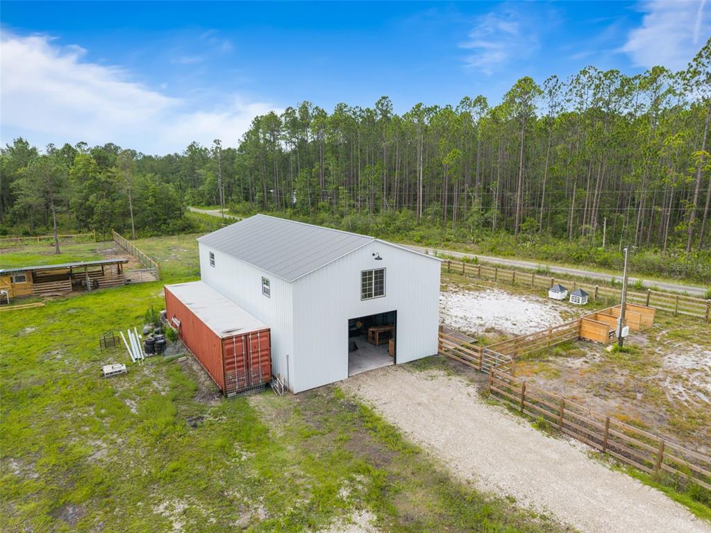 An aerial view of a white metal barn with an attached shipping container on rural land — TBD RETREAT ROAD, KEYSTONE HEIGHTS, FL