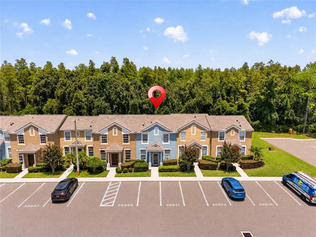 An exterior view of a multi-unit townhouse building with a parking lot in front — 30211 SWINFORD LANE, WESLEY CHAPEL, FL
