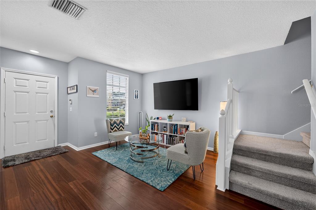 A living room features hardwood floors, a blue area rug, two chairs, and a staircase — 30211 SWINFORD LANE, WESLEY CHAPEL, FL