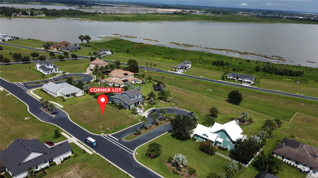 An aerial view shows a vacant corner lot situated in a residential neighborhood near water — 314 PULCHELLA WAY, LAKE ALFRED, FL