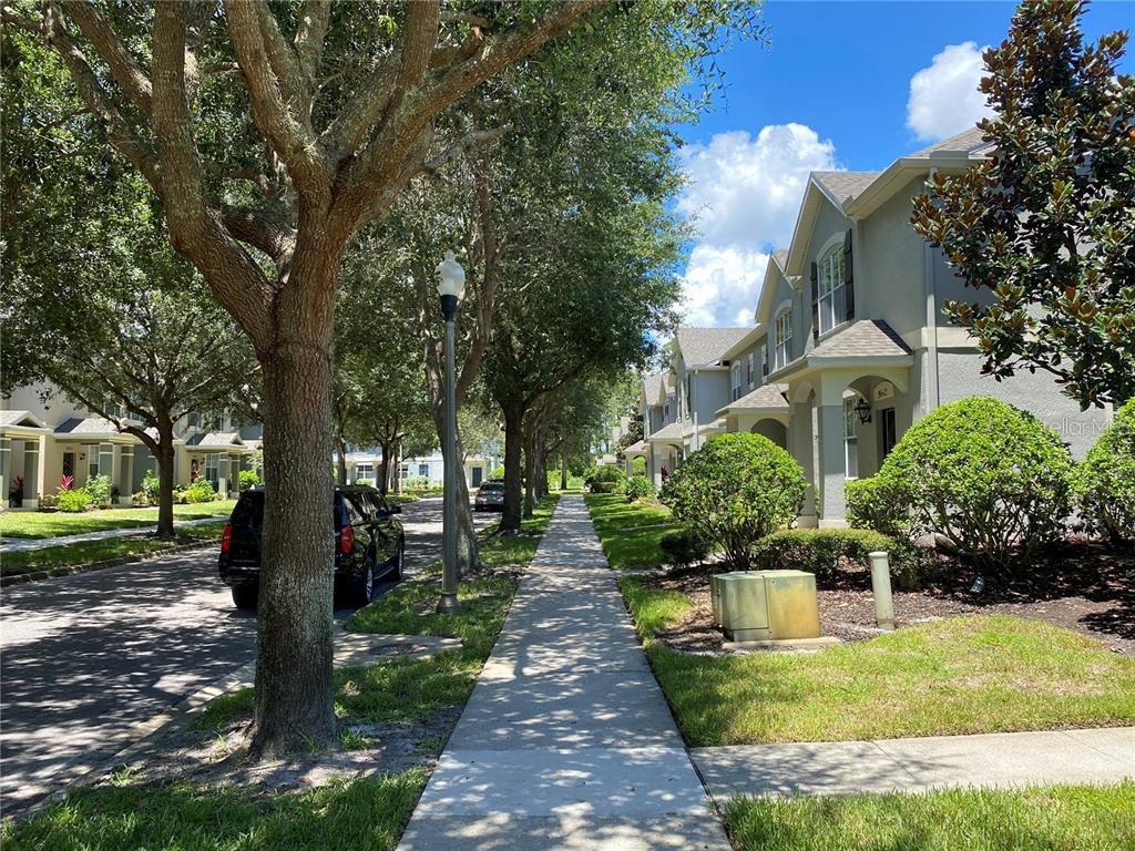 A paved driveway leads toward a row of garage doors next to a small pond — 12740 LANGSTAFF DRIVE, WINDERMERE, FL