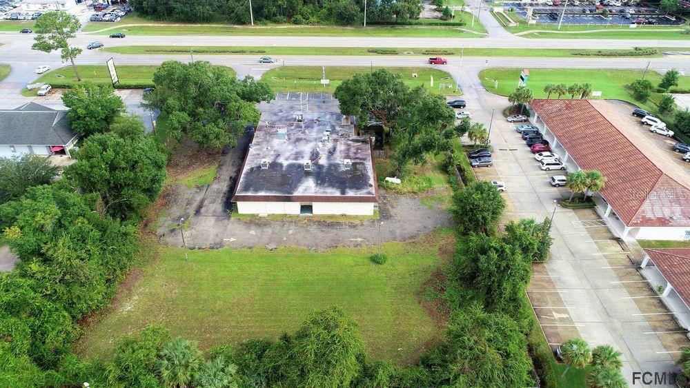 An aerial view shows a commercial building with a large parking lot and surrounding trees — 4701 E MOODY BOULEVARD, BUNNELL, FL
