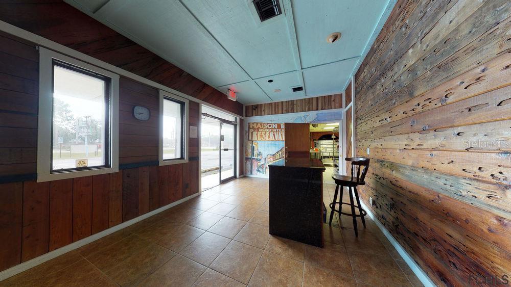 A commercial interior features wood-paneled walls, tile flooring, a dark counter, and a single stool — 4701 E MOODY BOULEVARD, BUNNELL, FL