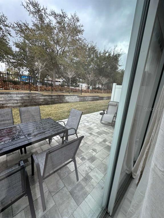 A patio with a dining set and a lounge chair overlooks a grassy yard — 7789 SPECTRUM DRIVE, REUNION, FL