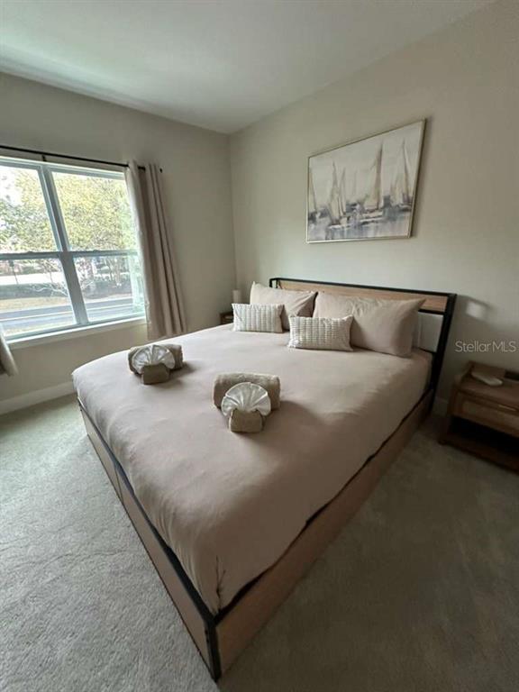 A bedroom features a bed with a tan comforter, two nightstands, and a sailboat painting — 7789 SPECTRUM DRIVE, REUNION, FL