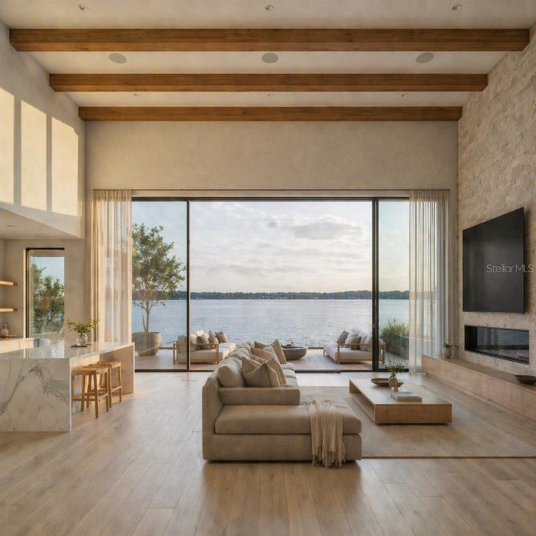 A modern living room features wood ceiling beams, a stone fireplace, and floor-to-ceiling lake views — 3802 MARIGOLD BELLE CIRCLE, CLERMONT, FL