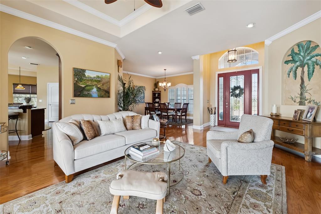 A living room with a beige sofa, armchair, glass coffee table, and hardwood floors — 3231 HARBOR BEACH DRIVE, LAKE WALES, FL