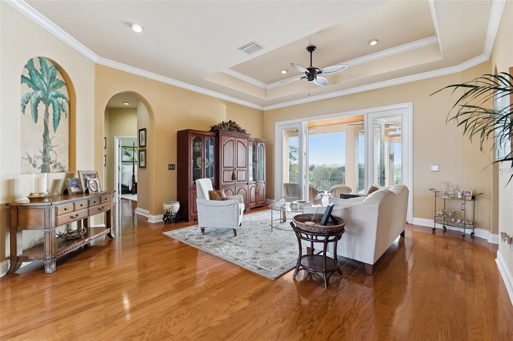 A living room with hardwood floors, a tray ceiling, and sliding doors opening to a balcony — 3231 HARBOR BEACH DRIVE, LAKE WALES, FL