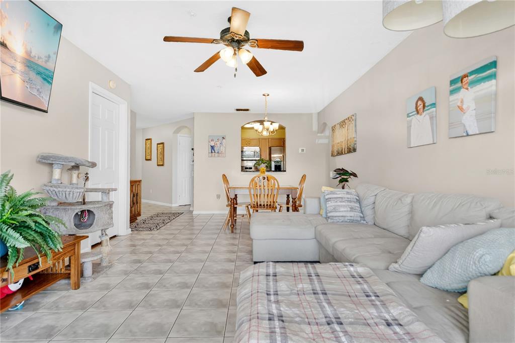 A living room with a gray sectional sofa, tiled floors, and a dining area nearby — 3930 SOUTHPOINTE DRIVE UNIT 214, ORLANDO, FL