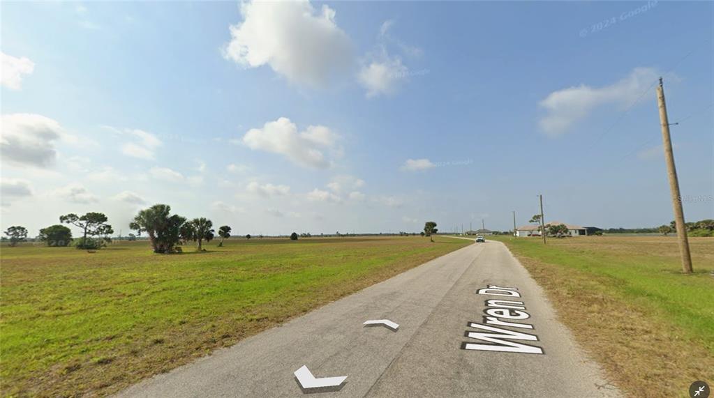 A paved road named Wren Dr runs through a large, flat, grassy vacant lot — 96 WREN DRIVE, PLACIDA, FL