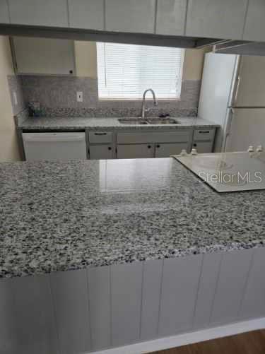 A kitchen features gray cabinets, granite countertops, a double sink, and a white dishwasher — 1000 LAKE OF THE WOODS BOULEVARD UNIT 201E, CASSELBERRY, FL