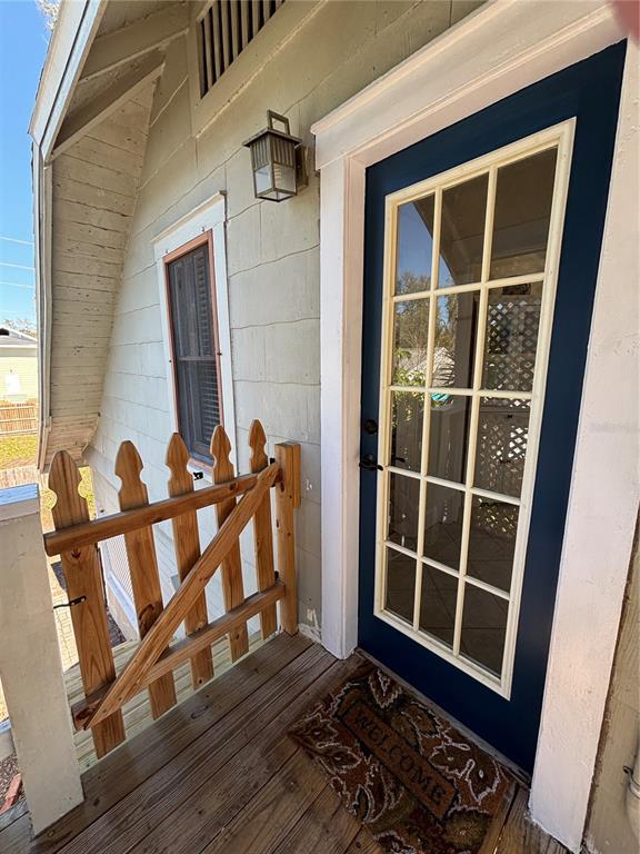 A wooden porch features a small gate, a dark blue door with glass panes, and a welcome mat — 810 22ND AVENUE N UNIT 2, ST PETERSBURG, FL