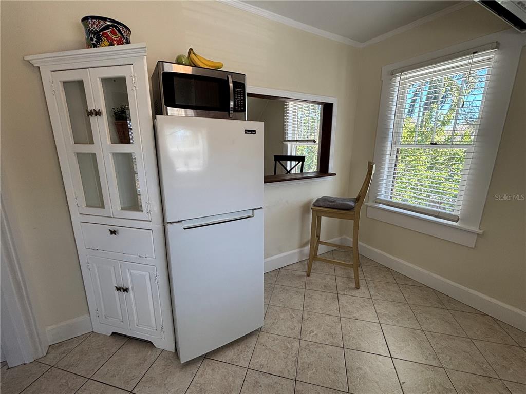 A kitchen corner features a white refrigerator, a tall cabinet, and a window with blinds — 810 22ND AVENUE N UNIT 2, ST PETERSBURG, FL
